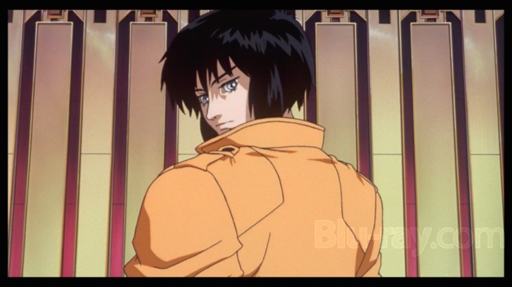 Film frame: the Major turning, amber jacket, lockers behind